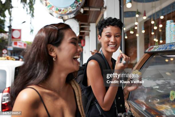 happy friends eating ice cream at store - spaghettibandjes stockfoto's en -beelden