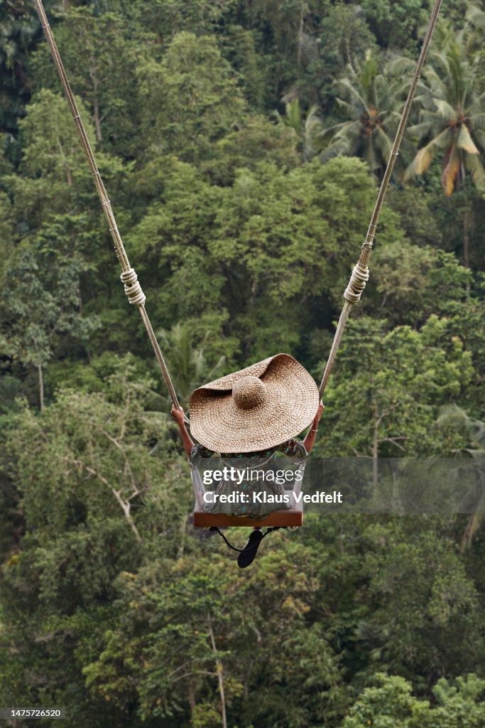 Woman swinging against forest during vacation