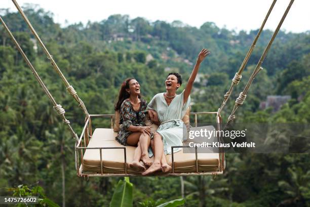 happy young women enjoying swinging during vacation - wonderlust stockfoto's en -beelden