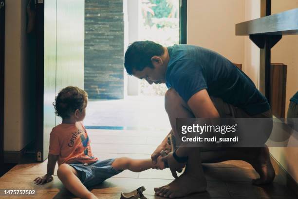 father helping his son put his shoes on - boy tying shoes stock pictures, royalty-free photos & images