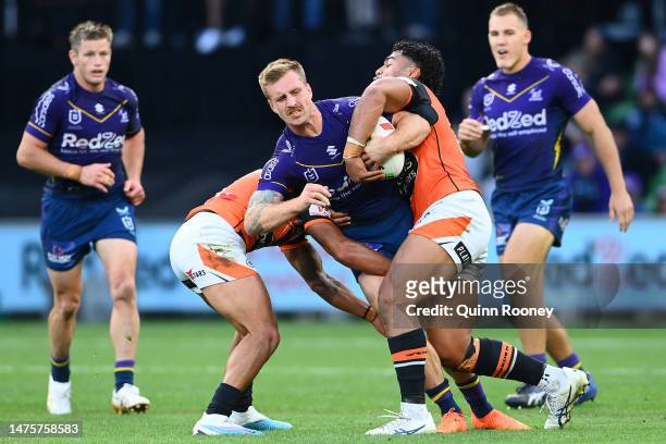 Cameron Munster of the Stormis tackled during the round four NRL match between the Melbourne Storm and Wests Tigers at AAMI Park on March 24, 2023 in...