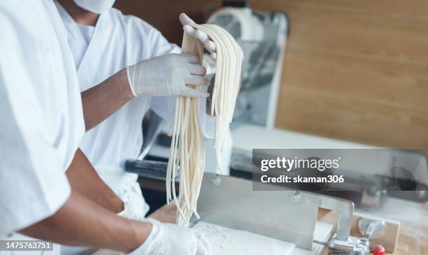 close up japanese chef's hands at work preparing fresh udon noodles. japanese food - udon photos et images de collection