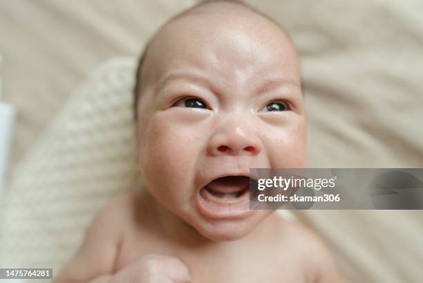 facial expression negative emotion asian newborn baby crying and lying down on the bed  during  mother changing cloth and baby diaper - doctor looking down stock pictures, royalty-free photos & images