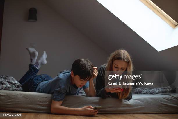 children teenagers brother and sister spending time together lying on bed, smartphones in their hands, discussing new items and formed - young sister stock pictures, royalty-free photos & images