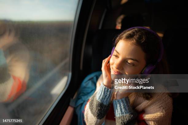 teenager-mädchen, das während der zugfahrt musik über kopfhörer hört - travel girl stock-fotos und bilder