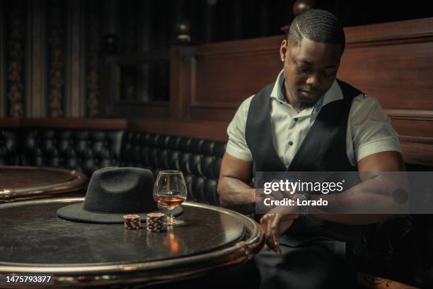 handsome black gangster man in a brown bar - bodyguard muscle stock pictures, royalty-free photos & images