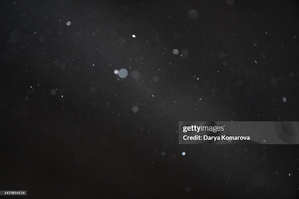 Dust flies against the background of a beam of light, isolated black background with copy space.