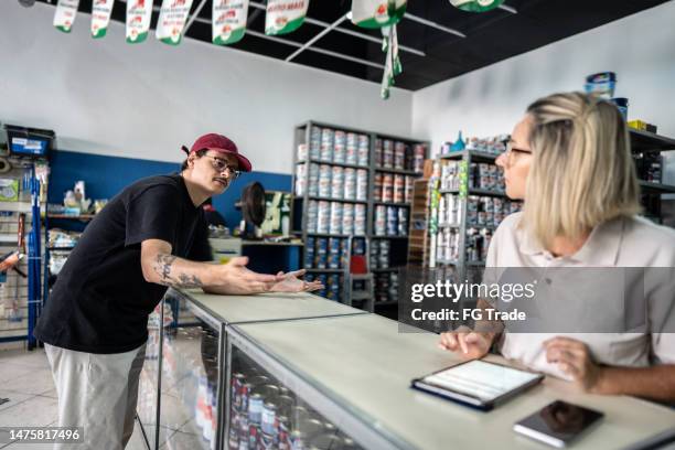 hombre adulto hablando con una vendedora en una tienda de pintura - quejándose fotografías e imágenes de stock