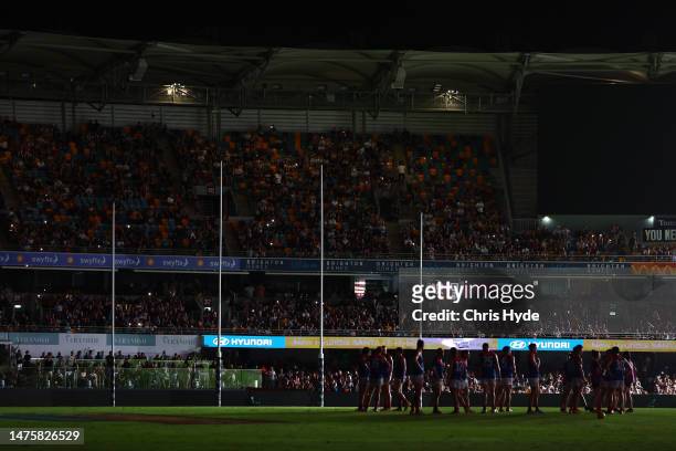 Players wait on field as power goes out during the round two AFL match between Brisbane Lions and Melbourne Demons at The Gabba, on March 24 in...