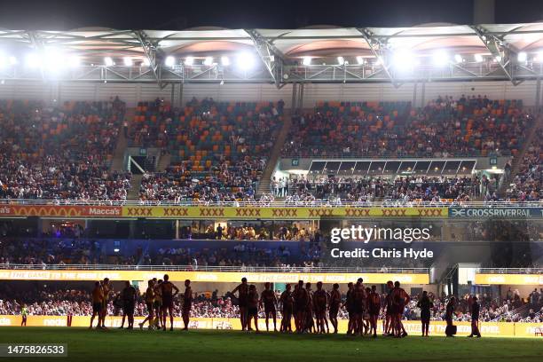 Players wait on field as power goes out during the round two AFL match between Brisbane Lions and Melbourne Demons at The Gabba, on March 24 in...