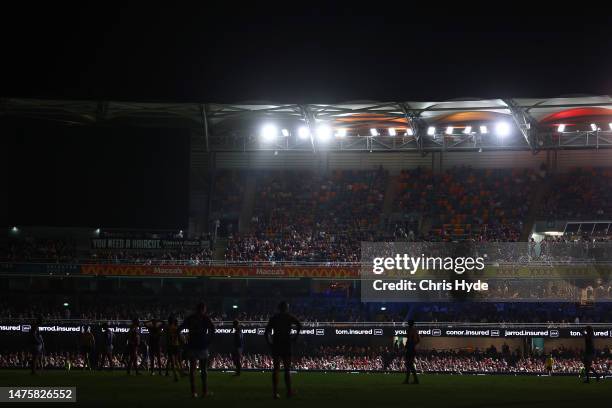 Players wait on field as power goes out during the round two AFL match between Brisbane Lions and Melbourne Demons at The Gabba, on March 24 in...