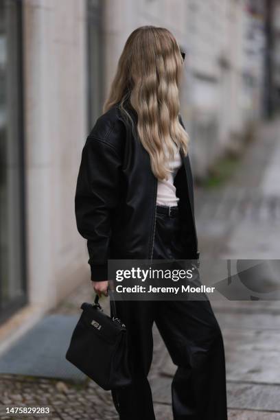 Isabelle Hartmann seen wearing Saint Laurent black sunglasses, silver earrings, Ivana Mentlova leather bomber jacket, COS transparent beige knit,...