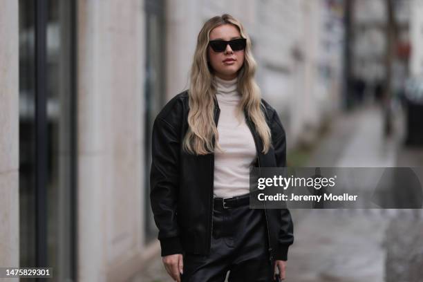 Isabelle Hartmann seen wearing Saint Laurent black sunglasses, silver earrings, Ivana Mentlova leather bomber jacket, COS transparent beige knit,...