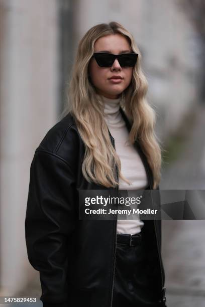 Isabelle Hartmann seen wearing Saint Laurent black sunglasses, silver earrings, Ivana Mentlova leather bomber jacket, COS transparent beige knit,...