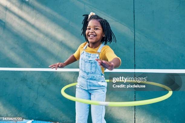 happy, playing and portrait of a child with a hula hoop for fitness, practice and hobby. smile, carefree and an african girl with a toy for happiness, playtime and break on a school playground - girls playing stock pictures, royalty-free photos & images