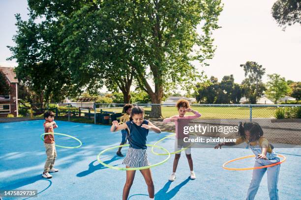 hula hoop, children and kids playing outdoors in a park together having fun in happiness and joy for fitness. exercise, bonding and young people practice and learning on school grounds on a break - vrijetijd sport en spel stockfoto's en -beelden