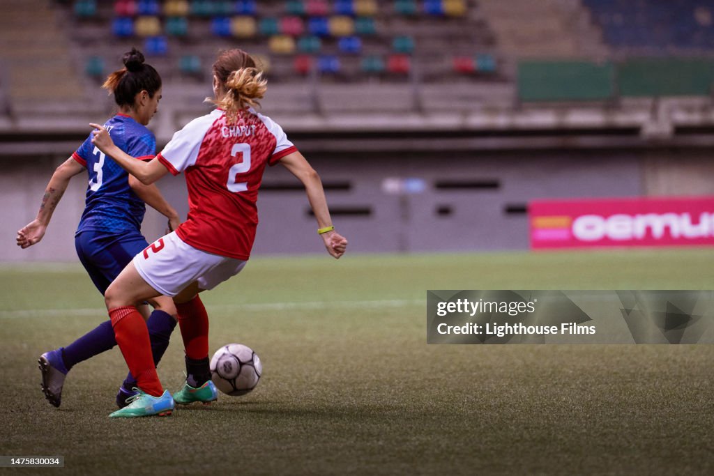 Two opposing professional soccer players compete for possession of the ball.