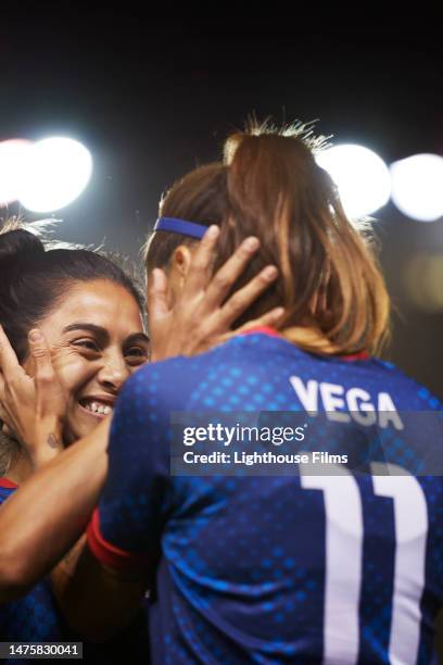 two soccer players grab each other's face with excitement. - womens champions league stock pictures, royalty-free photos & images