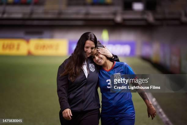 a professional soccer coach and her player walk off the field with joy. - tutor stockfoto's en -beelden