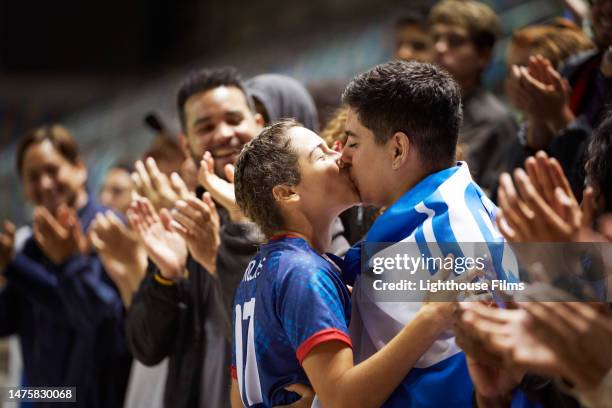 a female athlete and a fan share a kiss in the middle of a crowd. - partido rondas deportivas fotografías e imágenes de stock