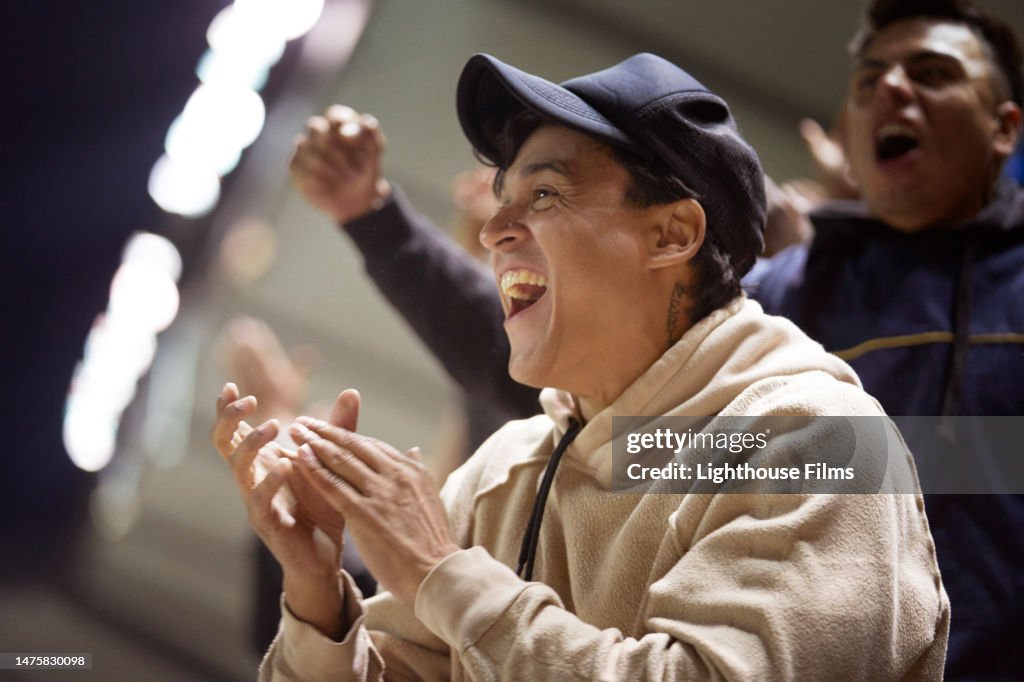 An excited sports fan claps with an enthusiastic smile.