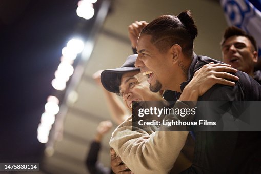 Two excited sports fans hug one another after a winning play.