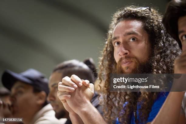 a man clenches his fist while he watches a sports game. - concentration curl stock pictures, royalty-free photos & images