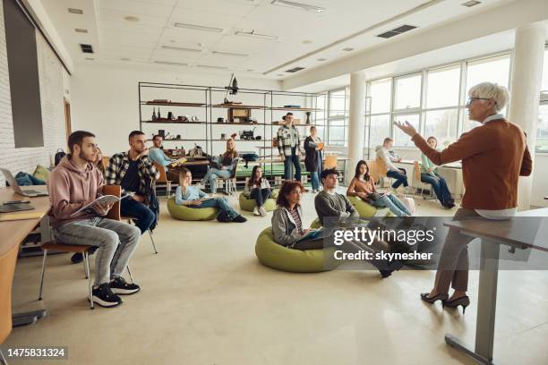 happy mature teacher giving a lecture in a casual classroom. - modern classroom stock pictures, royalty-free photos & images