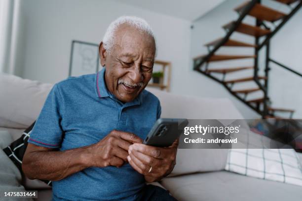 elderly man using smartphone at home - old man afro stock pictures, royalty-free photos & images