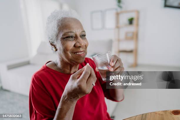 elderly woman taking medicine - happy senior medication stock pictures, royalty-free photos & images