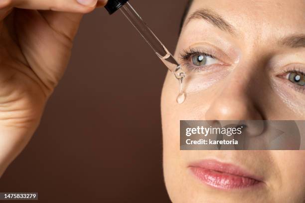 woman applying facial serum gel - thick white women fotografías e imágenes de stock