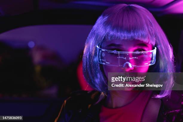 female portrait of woman who using eyeglasses for virtual reality in car. neon light concept photography, futuristic photo with color lighting indoors the vehicle. girl and neural networks, people and technology for communication. - red and pink outfit stock pictures, royalty-free photos & images