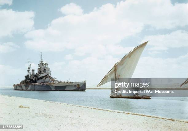 Howe, Flagship of the Commander in Chief, Pacific Fleet, Admiral Sir Bruce Fraser, passing through the Suez Canal behind a felucca on her way to join...