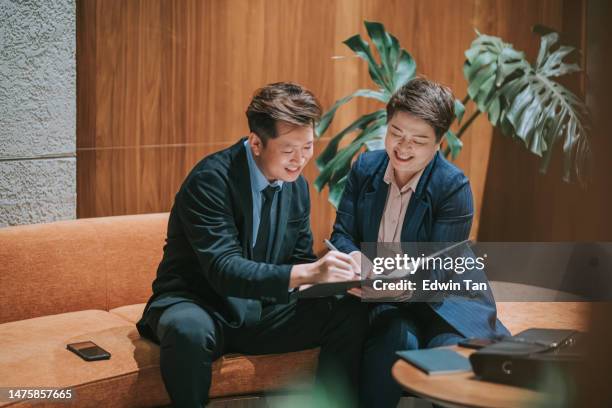 satisfied and happy asian business man signing document in hotel lobby - conference hotel stock pictures, royalty-free photos & images