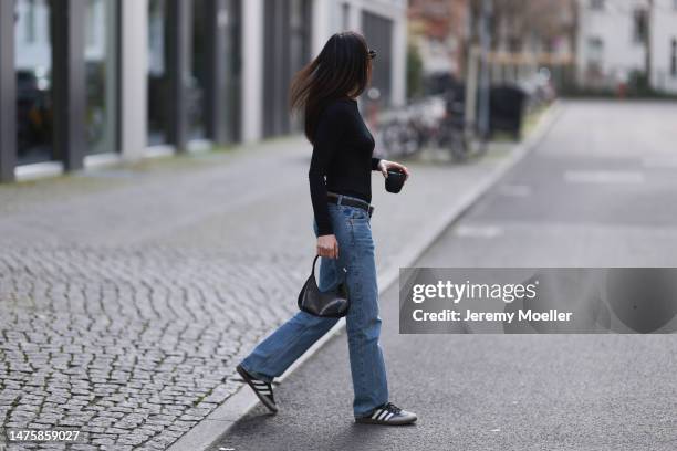 Anna Winter seen wearing Balenciaga black sunglasses, silver earrings, Prada black top with long sleeves, Weekday blue denim jeans, silver and black...