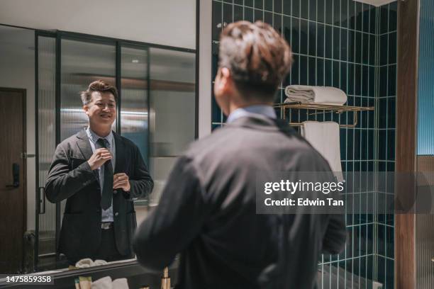 un homme d’affaires asiatique se prépare dans la salle de bain de l’hôtel devant le miroir - lavabo photos et images de collection
