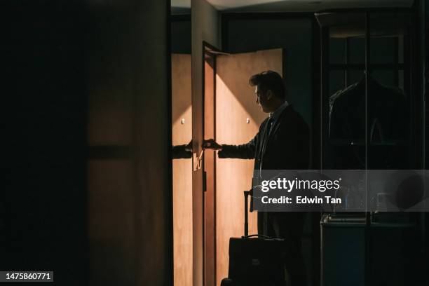 in der silhouette asiatischer chinesischer geschäftsmann, der in das hotelzimmer geht und die hotelschlüsselkarte einsteckt, aktiviert die elektrizität des zimmers - hotelzimmer tür stock-fotos und bilder