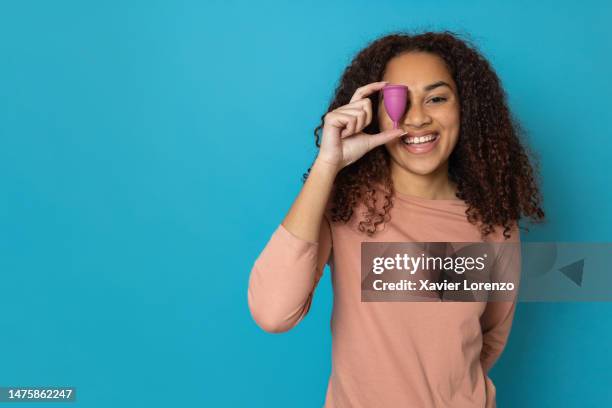 cheerful smiling woman showing eco-friendly menstrual cup at camera over isolated blue background with copy space. feminine higiene and period concept - higiene stock-fotos und bilder