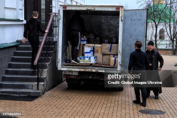 Men and a priest load a truck with packages and boxes of the Orthodox Church of the Moscow Patriarchate belongings on March 24, 2023 in Kyiv,...