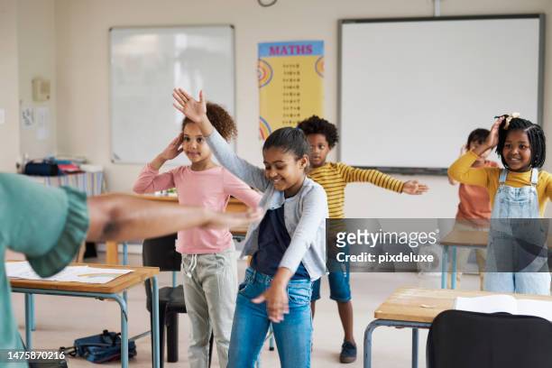 teacher, classroom and children dancing in fun group activity for learning, education or childhood development at school. little students moving dance in class for team exercise or listening skills - dancing classrooms stock pictures, royalty-free photos & images