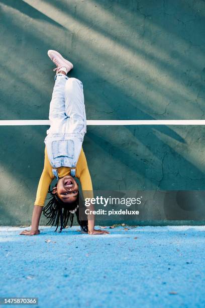 retrato, parada de manos y maqueta con una niña negra jugando sola al aire libre durante el recreo en la escuela. niños, boca abajo y jugando con una niña bromeando o divirtiéndose afuera en un patio de recreo o cancha - handstand fotografías e imágenes de stock