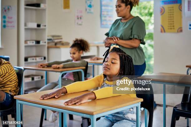teacher, classroom and child in meditation for learning, education or childhood development at school. little black girl student sitting at desk for listening test, calm activity or therapy in class - student wellbeing stock pictures, royalty-free photos & images