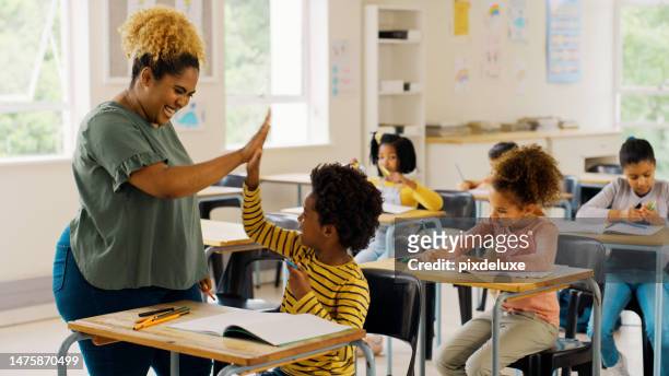 education, high five and teacher with children in classroom for learning, support and motivation. study, assessment and development with student and woman in school for celebration, exam and result - schoolhoofd stockfoto's en -beelden