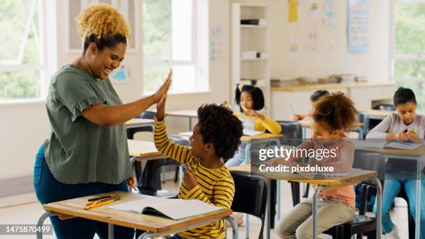 education, high five and teacher with children in classroom for learning, support and motivation. study, assessment and development with student and woman in school for celebration, exam and result - aluna imagens e fotografias de stock