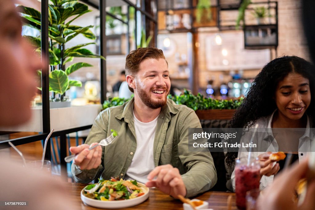 Junger Mann isst mit seinen Freunden in einem Restaurant