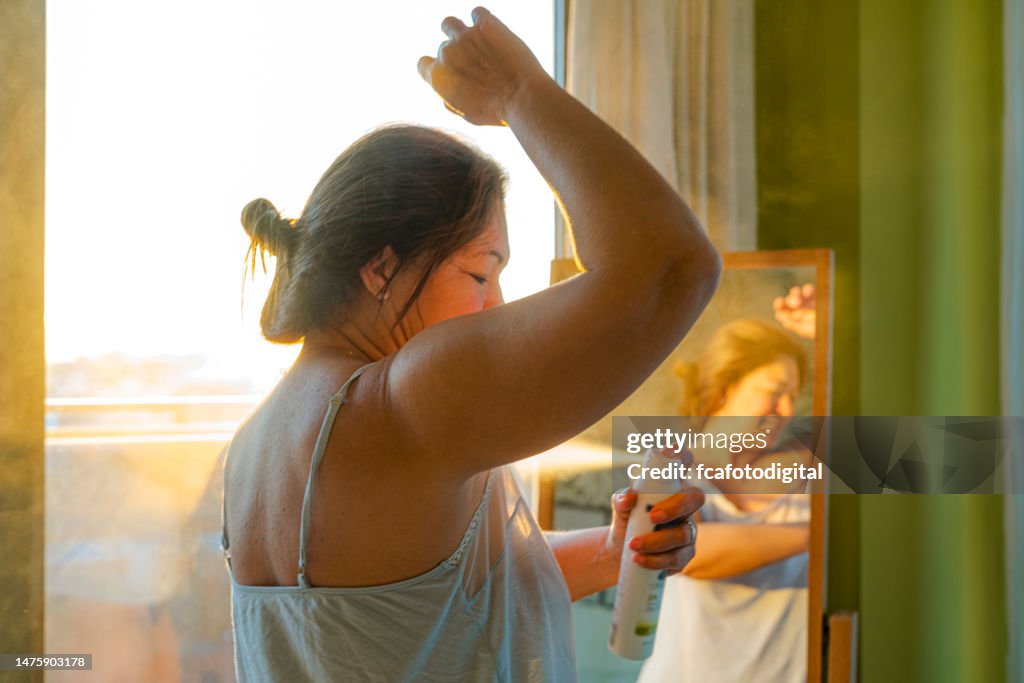 Woman applying deodorant on underarm