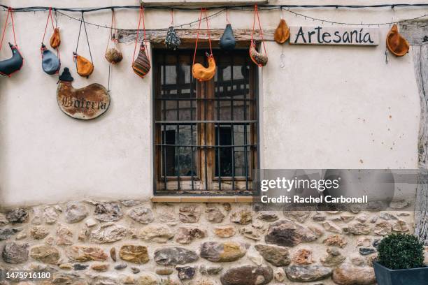 spanish leather wine botas hanging from a house´s facade. - covarrubias stock pictures, royalty-free photos & images