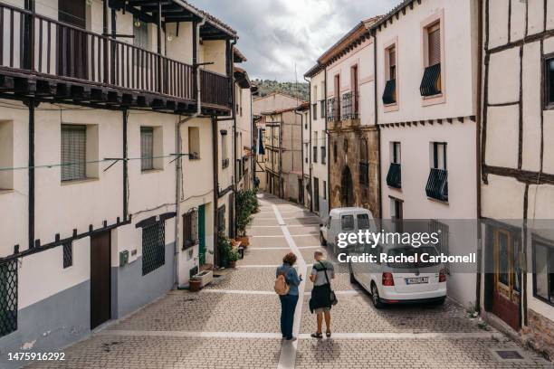 couple standing on the streets of the village passing by typical houses. - covarrubias stock pictures, royalty-free photos & images