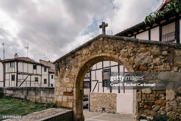 st thomas church´s stone arch with a cross and typical house. - covarrubias stock pictures, royalty-free photos & images