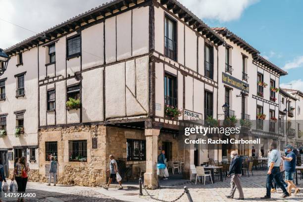people walking on the street passing by the typical houses in the village of cavarrubias. - covarrubias stock pictures, royalty-free photos & images